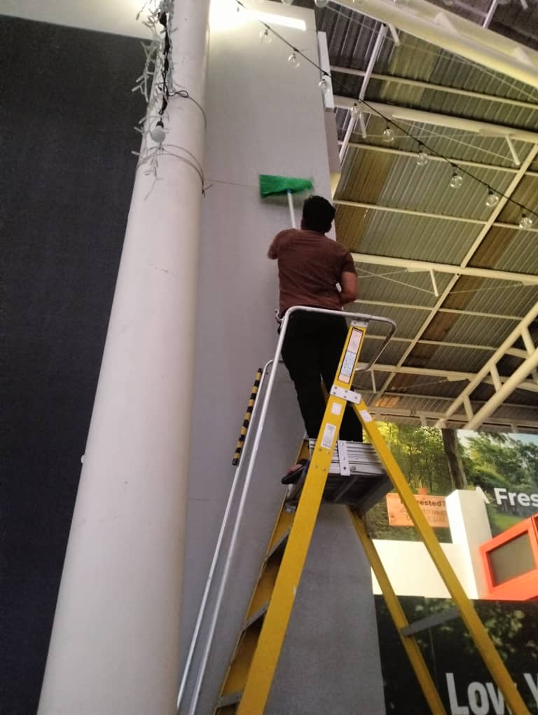 High-level dusting from a ladder in a retail space
